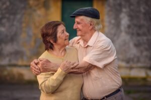 Charming elderly couple sharing a warm embrace outdoors, radiating love and joy.